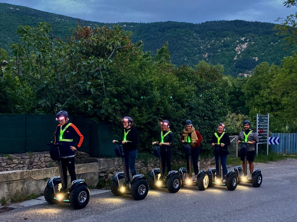 Sortie "Les Nocturnes" en gyropode à Montbrun-les-Bains, groupe posant sur les machines devant le beffroi