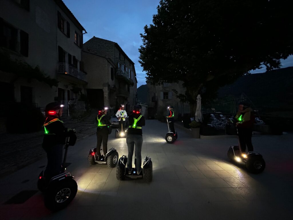 Sortie "Les Nocturnes" en gyropode à Montbrun-les-Bains, groupe posant sur les machines devant le beffroi